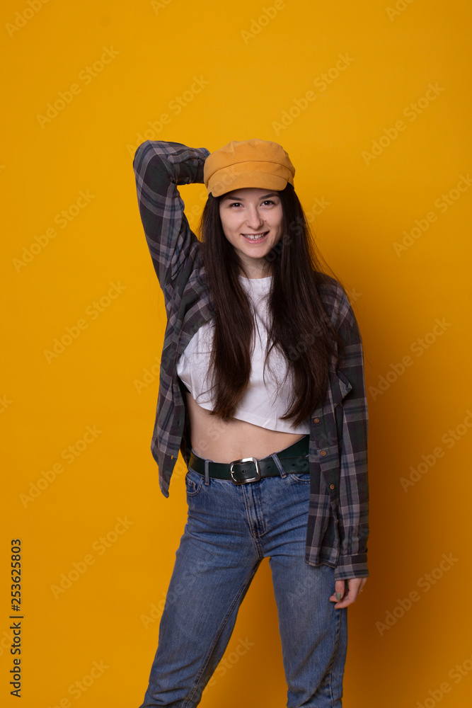 Excited young hipster woman in casual dress, widely smiling, looking at camera. Isolated on yellow background Excited young hipster woman in casual dress, widely smiling, looking at camera. Isolated on yellow background