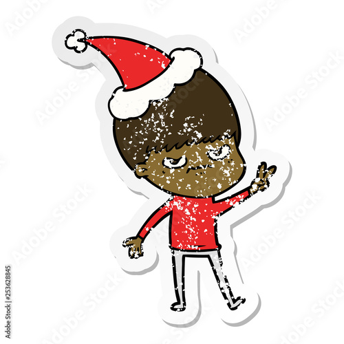 annoyed distressed sticker cartoon of a boy wearing santa hat