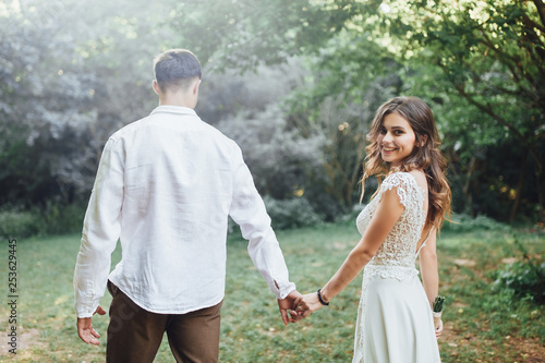 Groom and bride in may in the spring forest holding on hands! Love story!