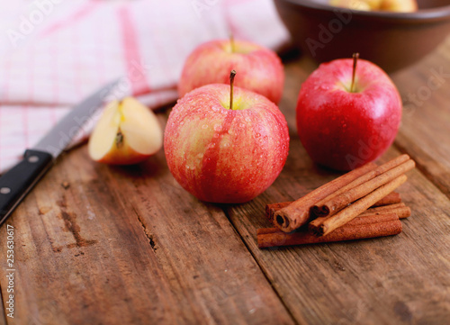 Red winter Apple with cinnamon sticks on rustic wooden table - close up