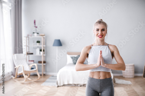 Woman balancing on one leg, doing tree yoga pose and meditating at home.