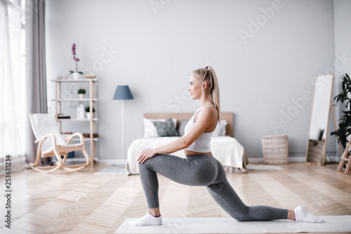 Young sporty woman doing morning exercise in living room.