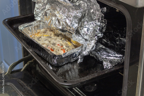 Baked meat with mushrooms in foil in the hot oven photo