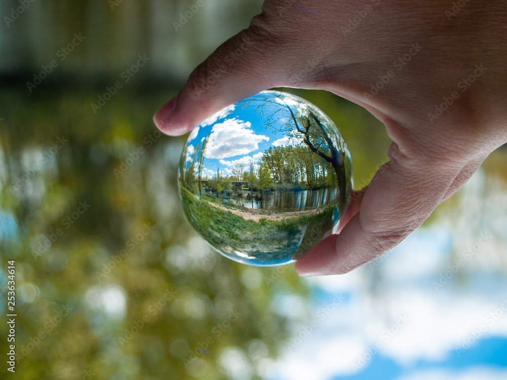 An unrecognizable person with a crystal ball in his hand with a landscape reflection