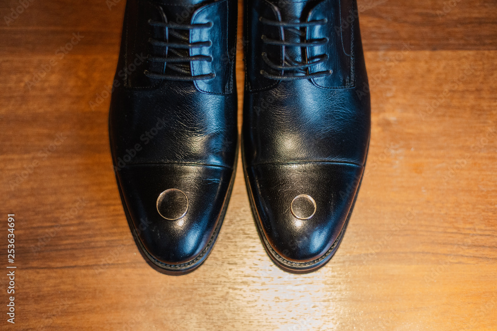 Gold wedding rings lie on the groom's shoes. Gold wedding rings lie on the groom's shoes.