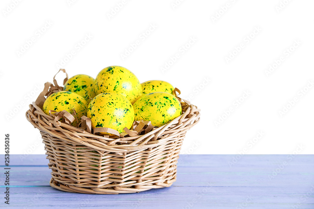 Easter yellow eggs in a straw basket. On blue wooden background. White isolate. Empty background.