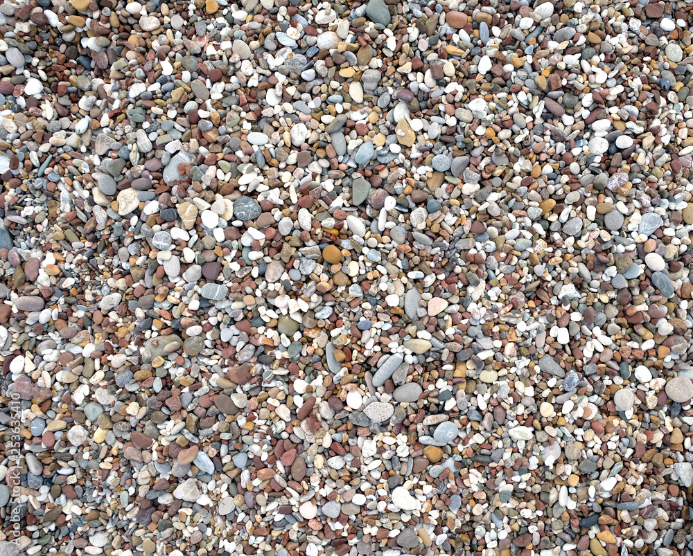 Background from many small smooth pebble stones on the sea beach on sunny day top view close-up Background from many small smooth pebble stones on the sea beach on sunny day top view close-up