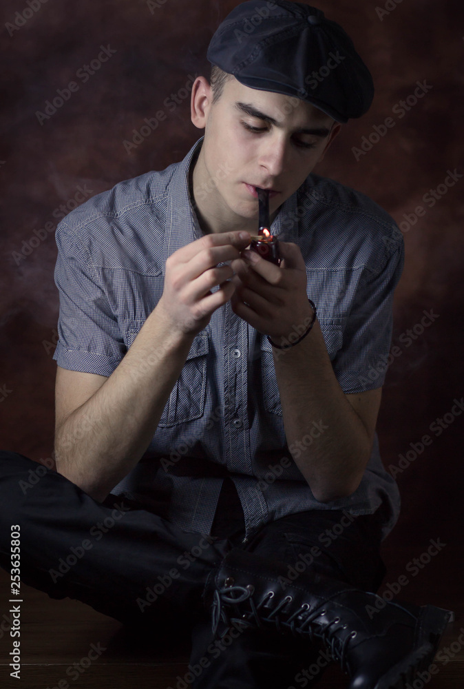 Portrait of young man with beret hat lighting a tobacco pipe. Retro concept Portrait of young man with beret hat lighting a tobacco pipe. Retro concept