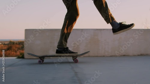 Close up of skateboarder ride in and out of frame, when riding through beautiful orange sunset on summer evening. Flow and chill, swaying with grace, practiced moves photo