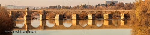 Old stone Roman bridge across Guadalquivir river in sunlight in Cordoba, Spain