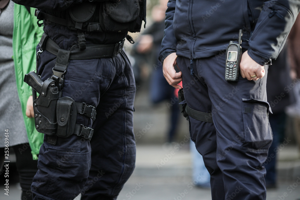Details of the security kit of a riot police officer, including handcuffs, 9mm handgun, radio station and baton Details of the security kit of a riot police officer, including handcuffs, 9mm handgun, radio station and baton
