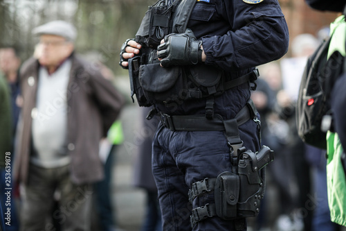 Details of the security kit of a riot police officer, including handcuffs, 9mm handgun, radio station and baton photo