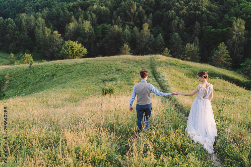 Romantic and happy caucasian couple in stylish clothes hugging on the background of beautiful nature. Love, relationships, romance, happiness concept. Man and woman walking outdoors together. Romantic and happy caucasian couple in stylish clothes hugging on the background of beautiful nature. Love, relationships, romance, happiness concept. Man and woman walking outdoors together.