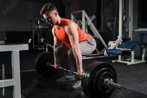 Strong handsome fit man exercising in the gym. Personal trainer workout. Athletic man working out his muscles at deadlift. Fitness, healhty lifestyle, bodybuilding concept.
