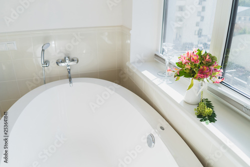 Coziness at home. Modern interior design. Bouquet of flowers near the window in the bathroom.