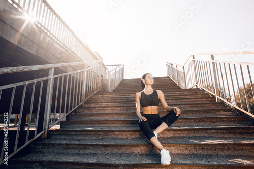 Young sexy woman jogger athlete training on road. Concept of healthy lifestyle. Female fitness model working out outdoor in city on the steps.