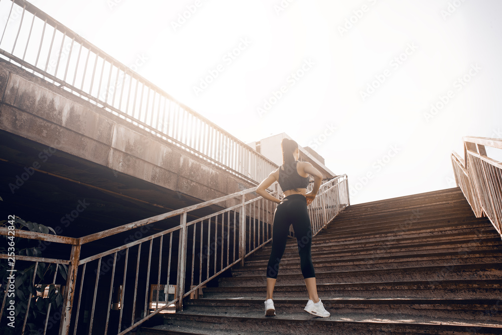 Young sexy woman jogger athlete training on road. Concept of healthy lifestyle. Female fitness model working out outdoor in city on the steps.