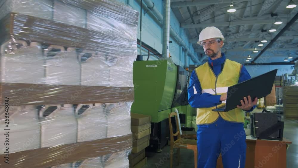 White plastic canisters are getting packaged under control of a technician White plastic canisters are getting packaged under control of a technician