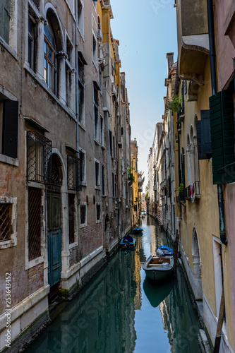 Italy, Venice, BOATS MOORED ON CANAL AMIDST BUILDINGS IN CITY © SkandaRamana