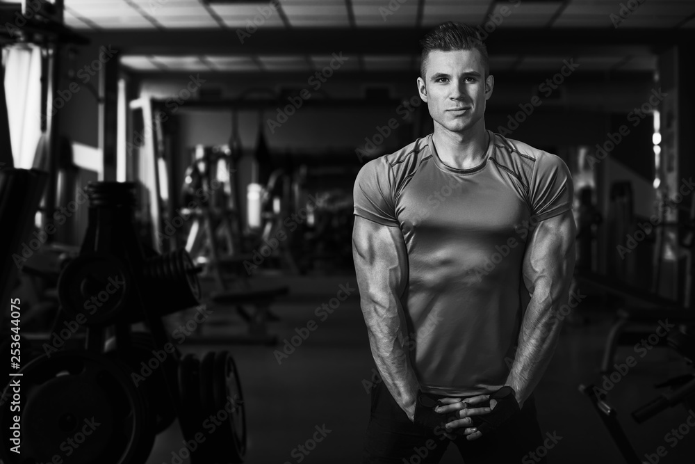 Muscular model sports young man exercising in gym. Black and white ...