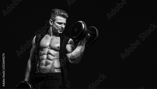 Muscular model sports young man exercising with dumbbell on dark background. Portrait of sporty healthy strong muscle. Sport workout bodybuilding motivation concept. Sexy torso.