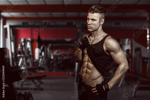 Muscular model young man exercising in gym. Portrait of sporty strong muscle. Fitness trainer. Sport workout bodybuilding motivation concept. Sexy naked torso, six pack abs. Male flexing his muscles.