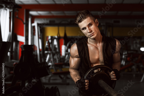 Muscular model young man exercising in gym. Portrait of sporty strong muscle. Fitness trainer. Sport workout bodybuilding motivation concept. Sexy naked torso, six pack abs. Male flexing his muscles. © KDdesignphoto