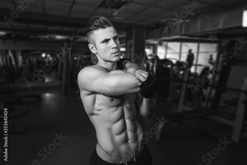 Muscular model sports young man exercising in gym. Black and white portrait of strong muscle. Fitness trainer. Sport workout bodybuilding motivation concept. Sexy torso.