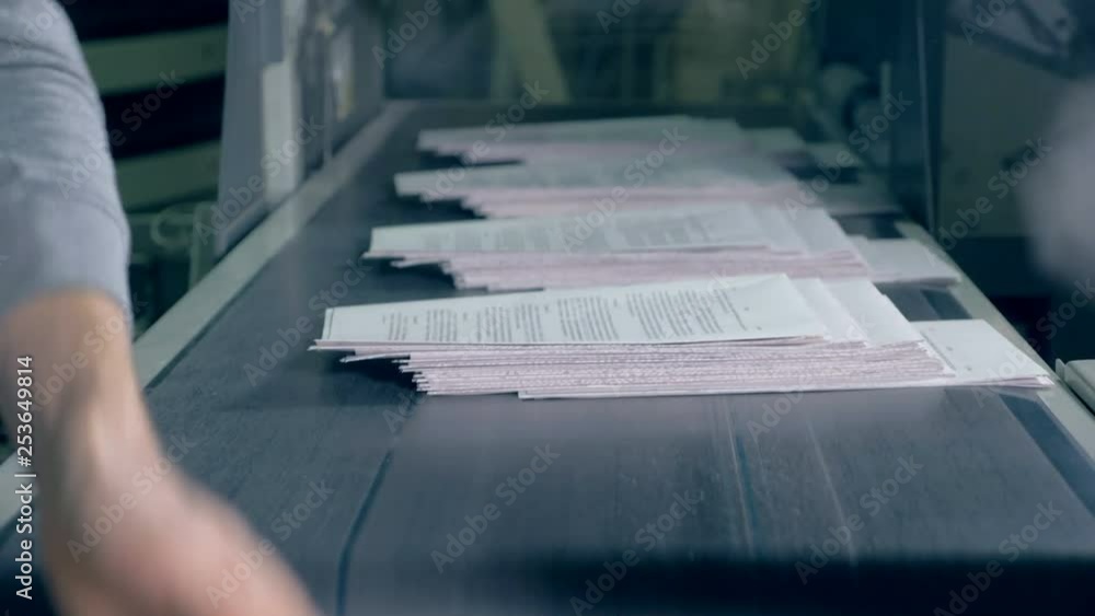 People take paper from typographical conveyor, close up. People take paper from typographical conveyor, close up.