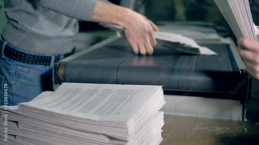 Men work with paper, stacking it, close up.