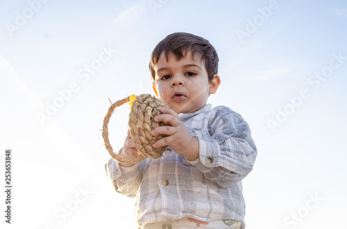 portrait of two years old toddler holding bascet with two easter eggs - golden hour photo