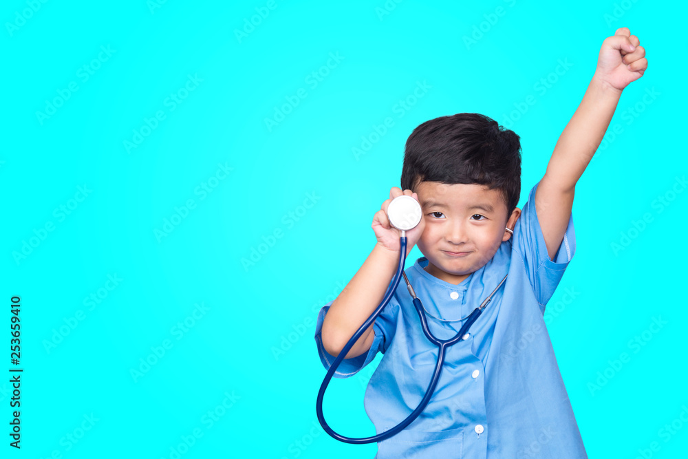 Smiling Asian kid in blue medical uniform holding stethoscope looking at camera on blue green background with copy space, healthy concept. Smiling Asian kid in blue medical uniform holding stethoscope looking at camera on blue green background with copy space, healthy concept.