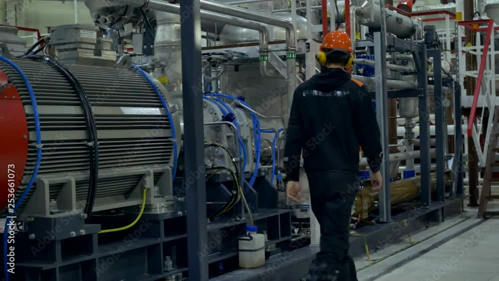A mechanic inspects a compressor unit at work. A mechanic inspects a compressor unit at work.