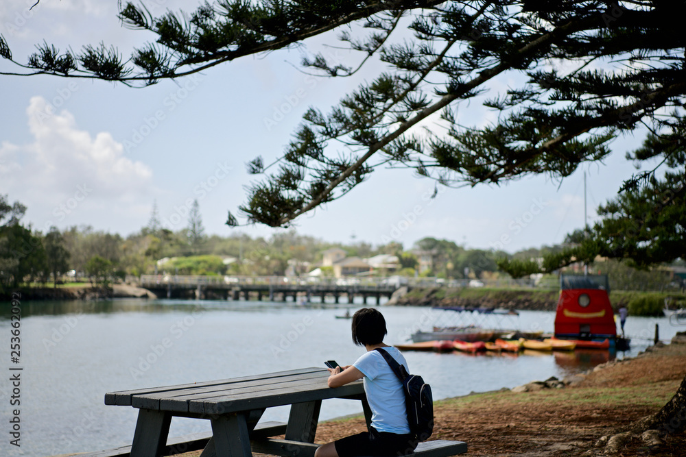 Woman with mobile phone sitting on park bench wth view Woman with mobile phone sitting on park bench wth view