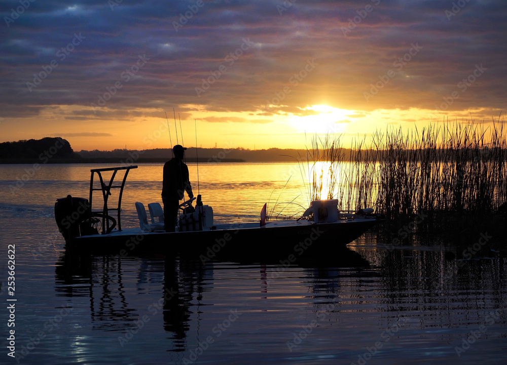 Unrecognizable Fisherman Moves His Boat into Position as the Sun Comes Up