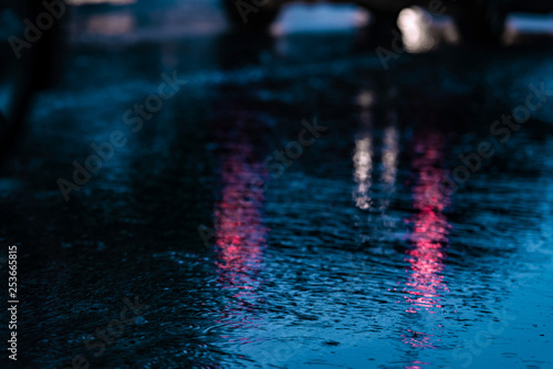 Night road blurred. Headlight of car in the dark while heavy raining. Rain in the city. Road, pavement, close up. Water splashes, spills on roadway © Elena