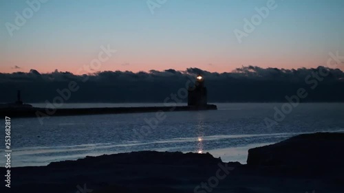 Iconic Lighthouse stands alone in frozen, steaming Lake Michigan harbor, Winter dawn time lapse. photo