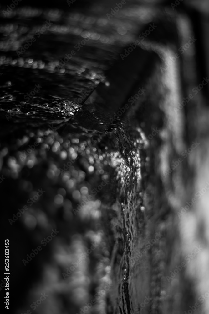 Close Up of Water Flowing Over the Edge of a Dark Stone Water Fountain Close Up of Water Flowing Over the Edge of a Dark Stone Water Fountain