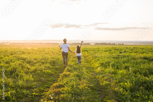Family, summer and holiday concept - little daughter and mother run in the summer field © satura_