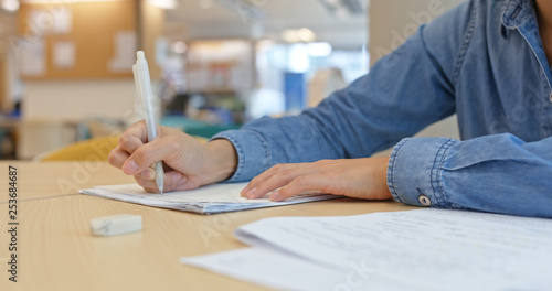 Woman write on the paper with cellphone at home