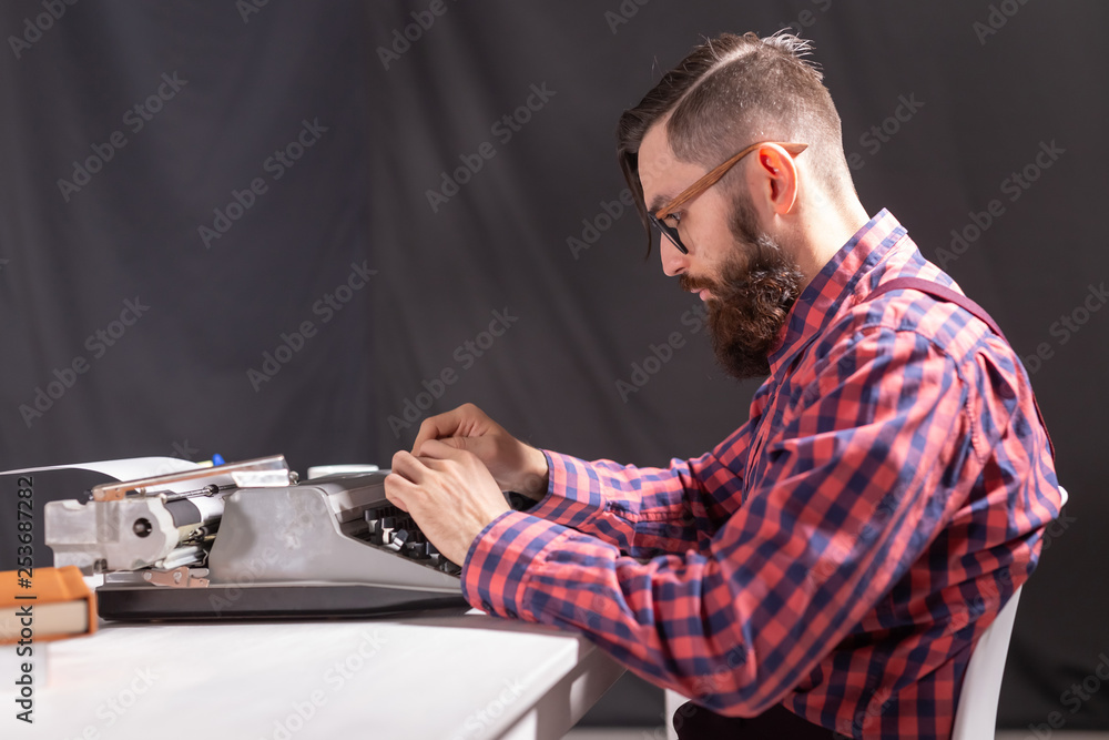 People and technology concept - Side view handsome man with beard working on typewriter over black background People and technology concept - Side view handsome man with beard working on typewriter over black background