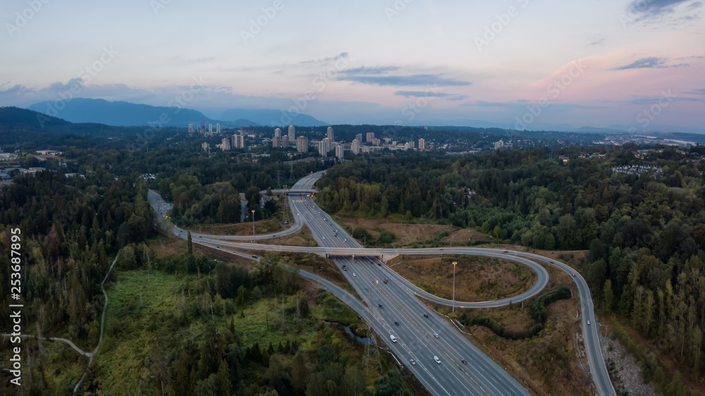 Aerial panoramic view of a highway entrance and exit in the modern city during a vibrant summer sunset. Taken in Burnaby, Greater Vancouver, BC, Canada. Aerial panoramic view of a highway entrance and exit in the modern city during a vibrant summer sunset. Taken in Burnaby, Greater Vancouver, BC, Canada.