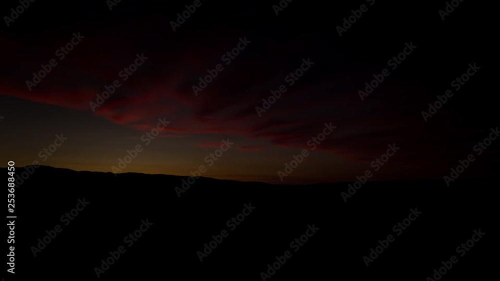 sun rising over desert valley riverbed full of trees with orange glowing clouds in the sky sun rising over desert valley riverbed full of trees with orange glowing clouds in the sky