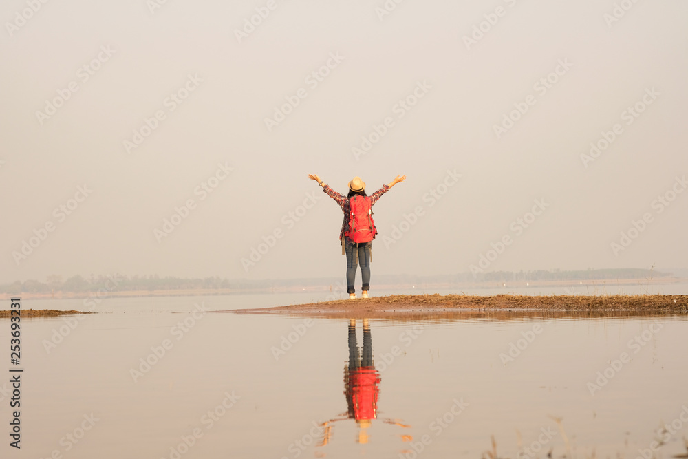 Tourist woman relaxing alone with a large backpack enjoying in lake view. Travel wanderlust lifestyle concept adventure vacations outdoor, Summer holiday and vacation trip Tourist woman relaxing alone with a large backpack enjoying in lake view. Travel wanderlust lifestyle concept adventure vacations outdoor, Summer holiday and vacation trip