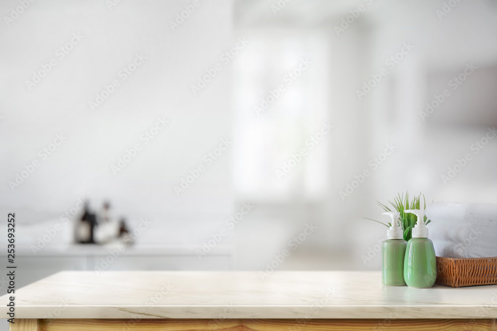 Fototapeta premium Ceramic shampoo bottle with white towels on marble counter in bathroom background