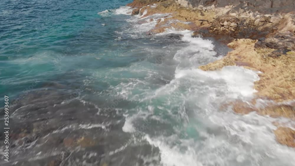 Aerial shot. The surf, the waves splashing blue and turquoise and the volcanic coastline of stones and dried petrified lava, Tenerife, Canary Islands, Spain. Dolly shot close-up The concept of a Aerial shot. The surf, the waves splashing blue and turquoise and the volcanic coastline of stones and dried petrified lava, Tenerife, Canary Islands, Spain. Dolly shot close-up The concept of a