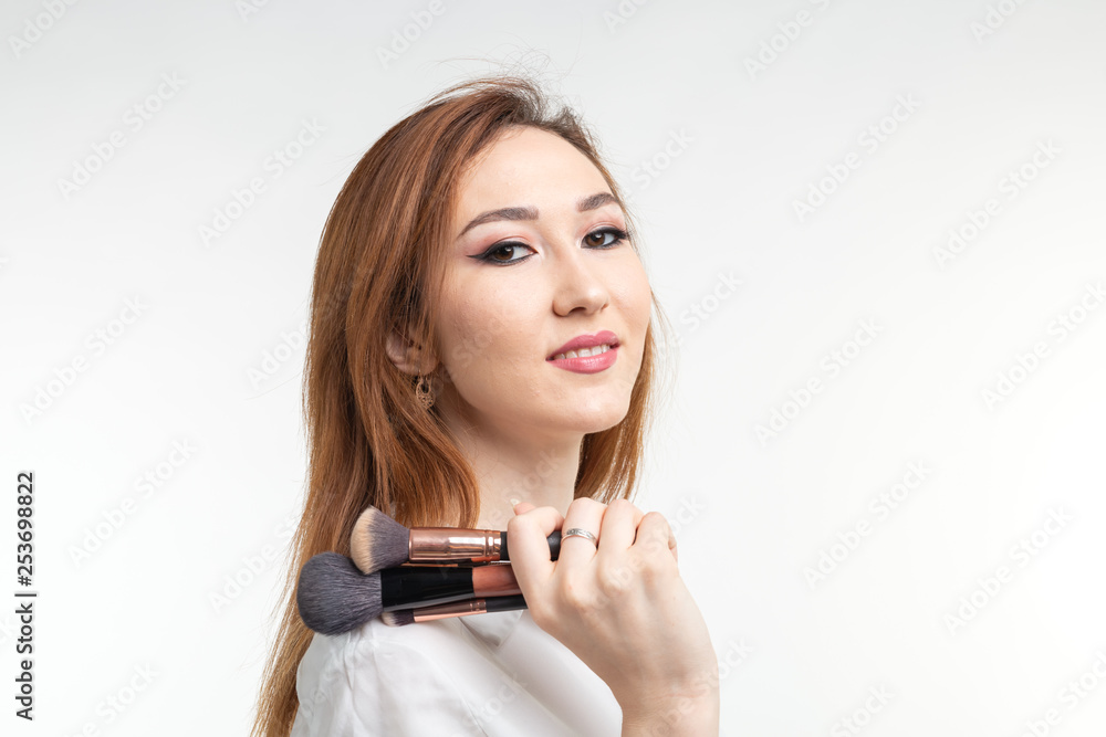 Attractive visagist or korean make-up artist holding a makeup brushes on white background Attractive visagist or korean make-up artist holding a makeup brushes on white background