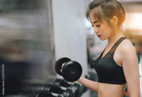 Woman with dumbbell workout exercise muscle building strong heavy weight in fitness gym and healthy lifestyle her bicep muscle basic training © Kiattisak