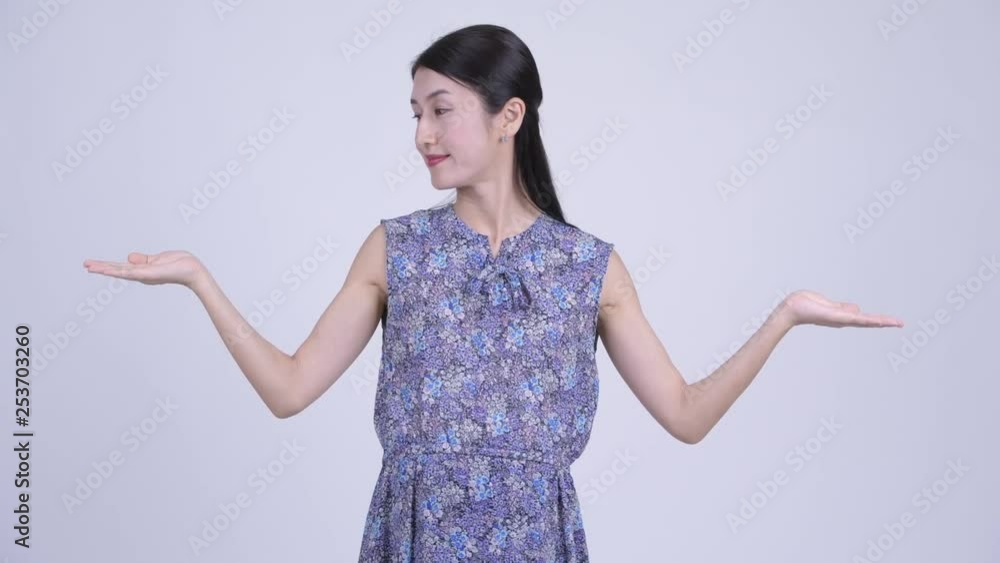 Happy pregnant Asian woman comparing something Happy pregnant Asian woman comparing something