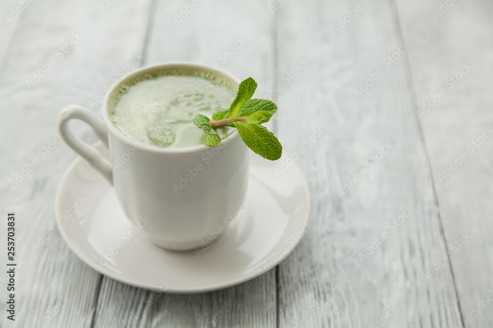 cup of hot matcha green tea with branch of mint on a grey background cup of hot matcha green tea with branch of mint on a grey background